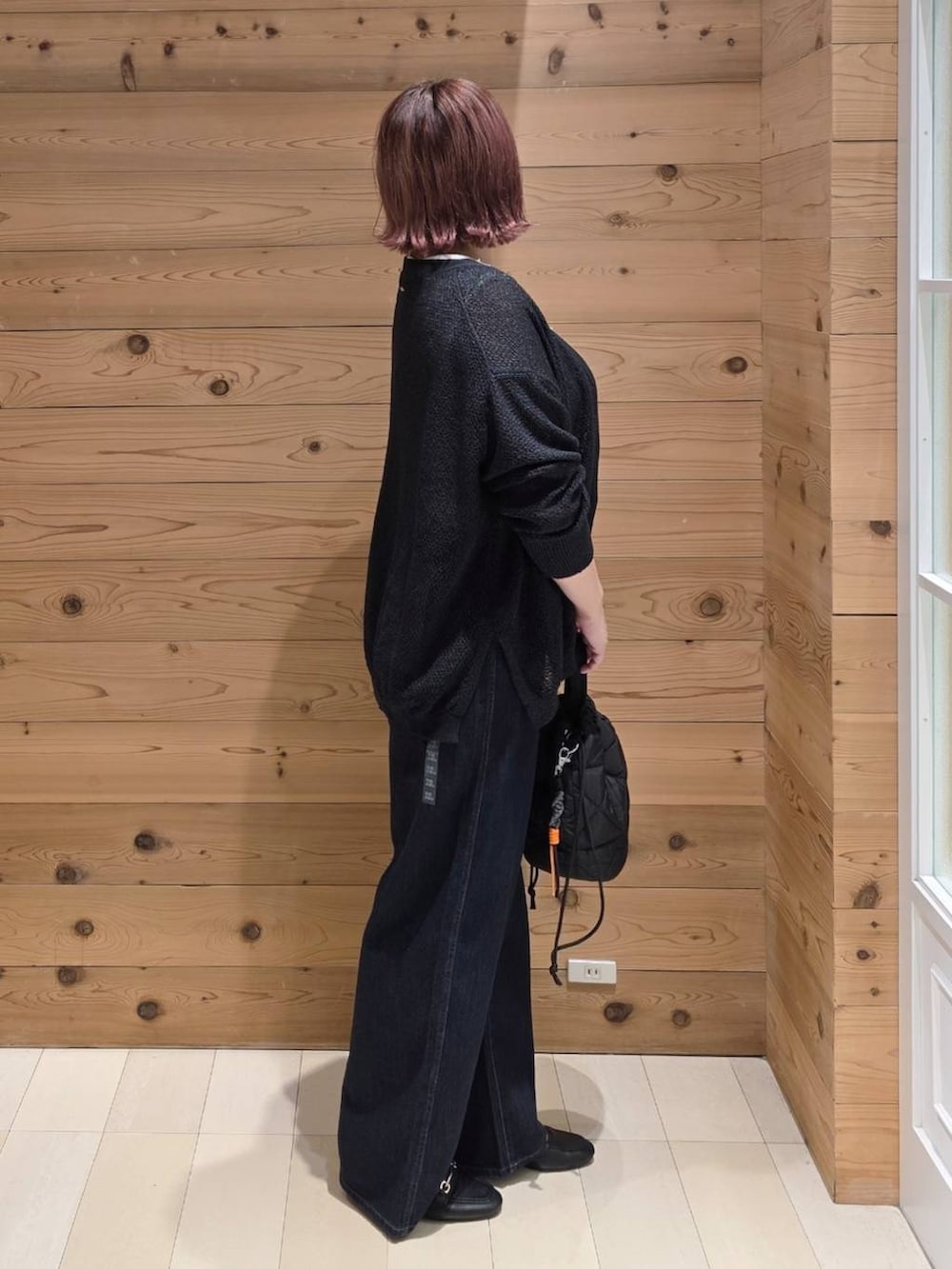 ブラック系のローファー、ブルー系のデニムパンツ、ブラック系のハンドバッグを着用したレディースの秋コーディネートの2枚目の写真