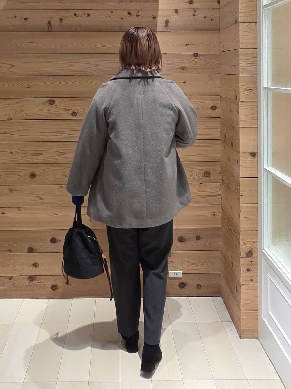 ブラウン系のチェスターコート、グレー系のニット/セーター、グレー系のその他パンツを着用したレディースの冬コーディネートの3枚目の写真