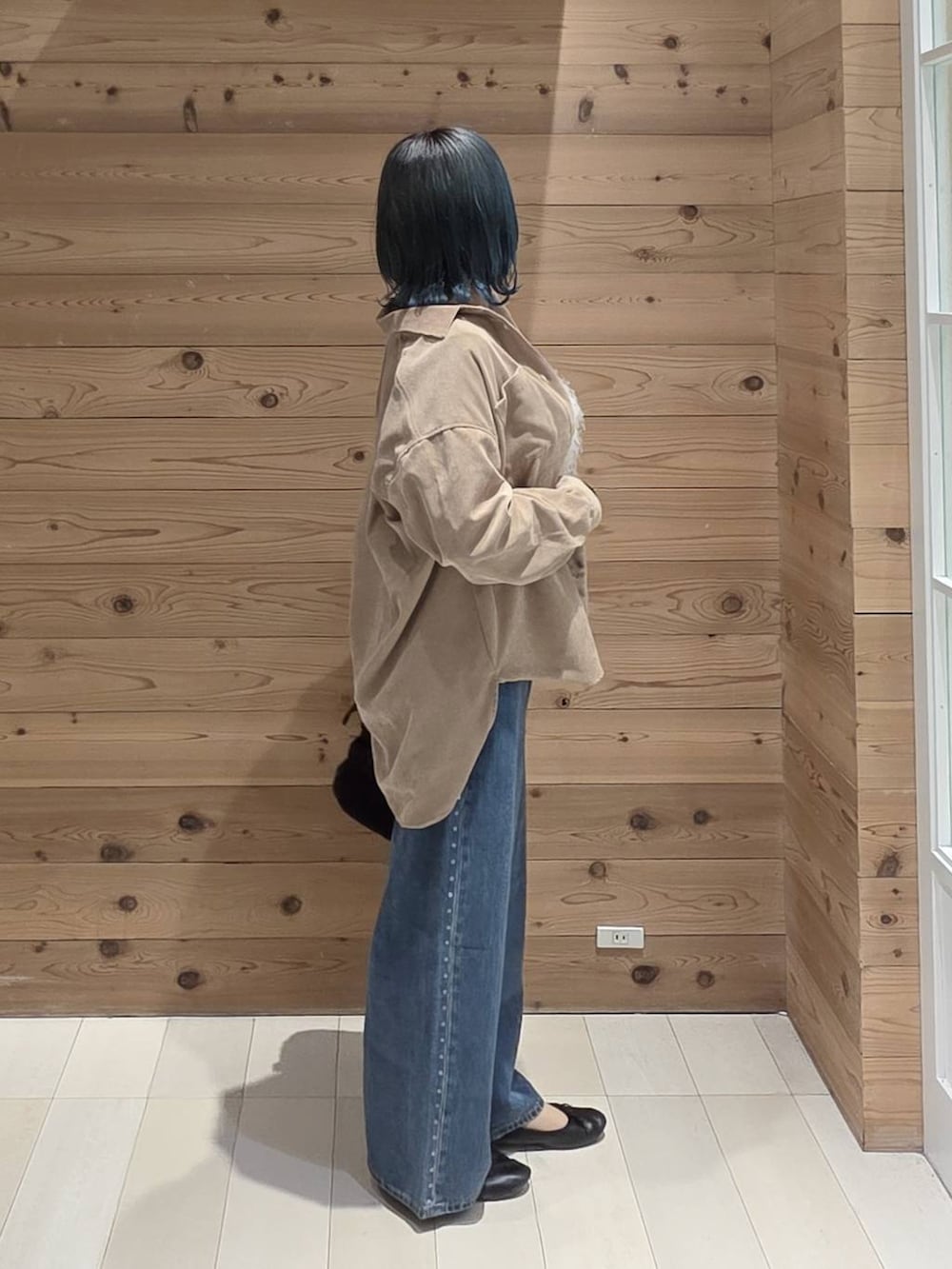 ブルー系のデニムパンツ、ブラック系のバレエシューズ、ブラック系のトートバッグを着用したレディースの秋コーディネートの2枚目の写真