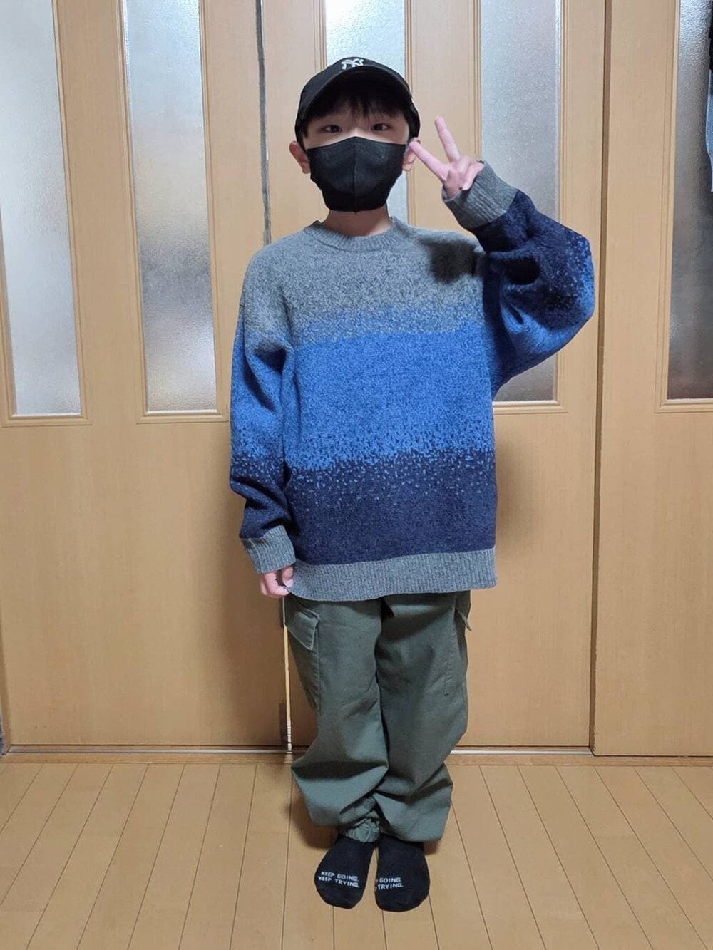 ベージュ系のブルゾン、グリーン系のカーゴパンツ、グレー系のニット/セーターを着用したキッズの冬コーディネートの2枚目の写真