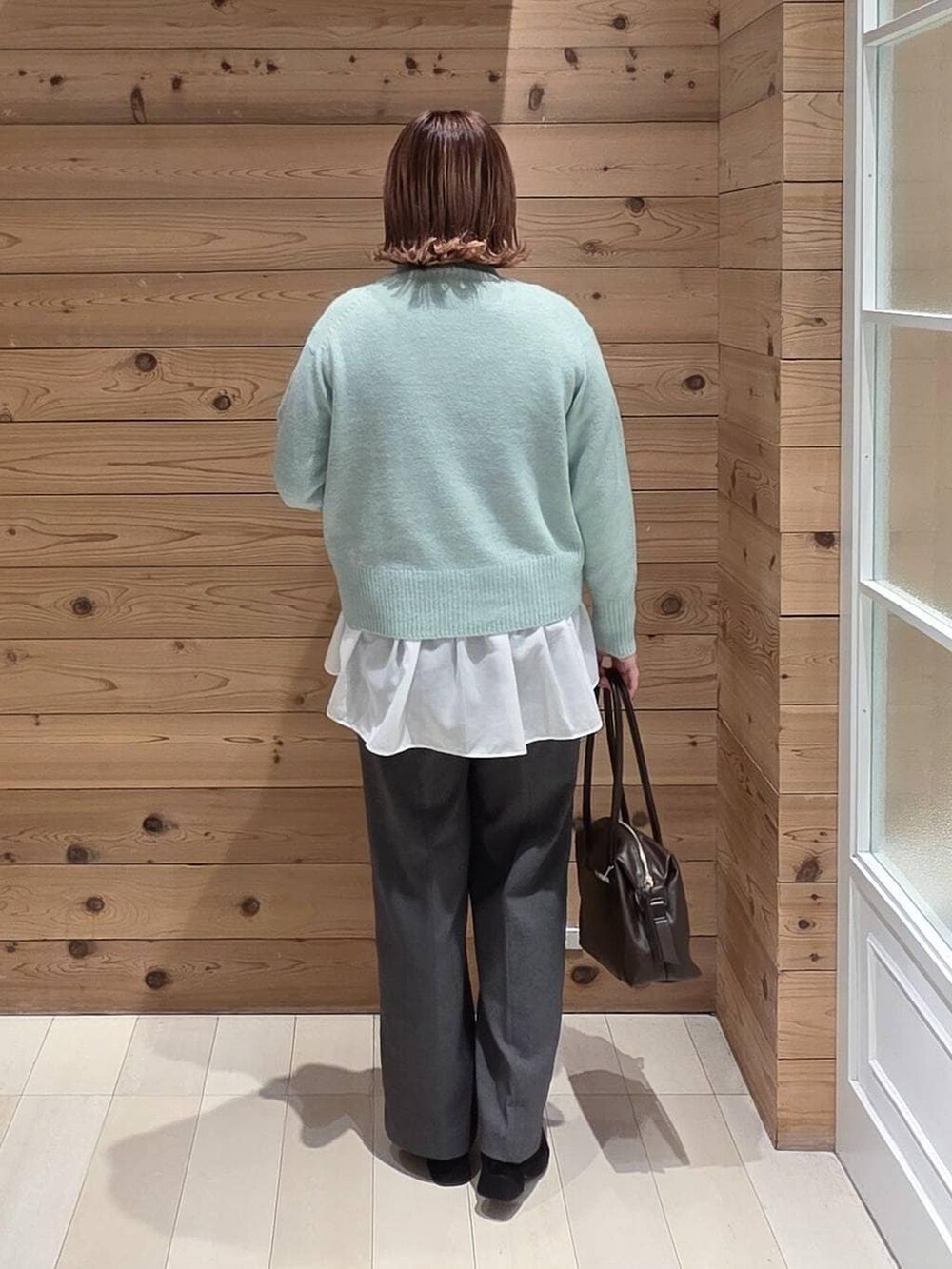 ベージュ系のブルゾン、ブラウン系のボストンバッグ、グリーン系のニット/セーターを着用したレディースの冬コーディネートの3枚目の写真