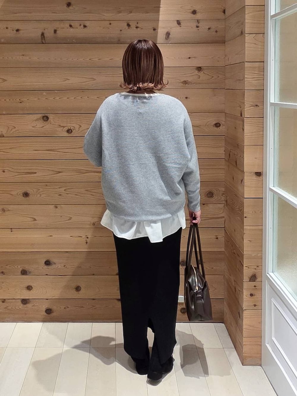 ブルー系のダウンジャケット/コート、ブラウン系のボストンバッグ、ホワイト系のTシャツ/カットソーを着用したレディースの冬コーディネートの3枚目の写真