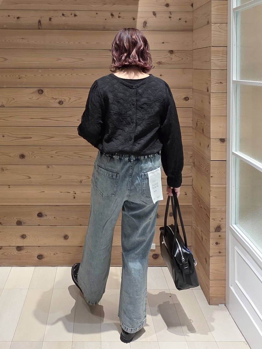 ブラック系のローファー、ブラック系のボストンバッグ、ブルー系のデニムパンツを着用したレディースの春コーディネートの4枚目の写真