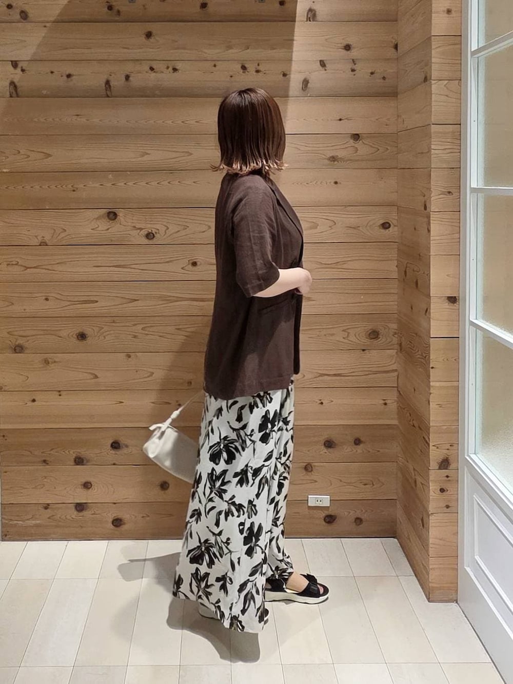 ブラウン系のテーラードジャケット、ホワイト系のその他パンツ、ブラック系のサンダルを着用したレディースの夏コーディネートの2枚目の写真