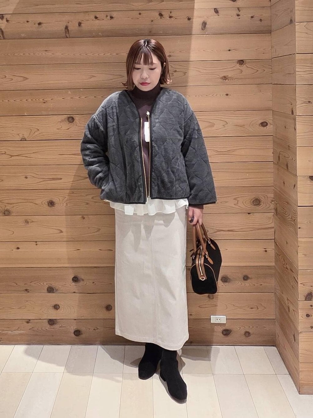 グレー系のブルゾン、グレー系のスカート、ホワイト系のTシャツ/カットソーを着用したレディースの冬コーディネートの4枚目の写真