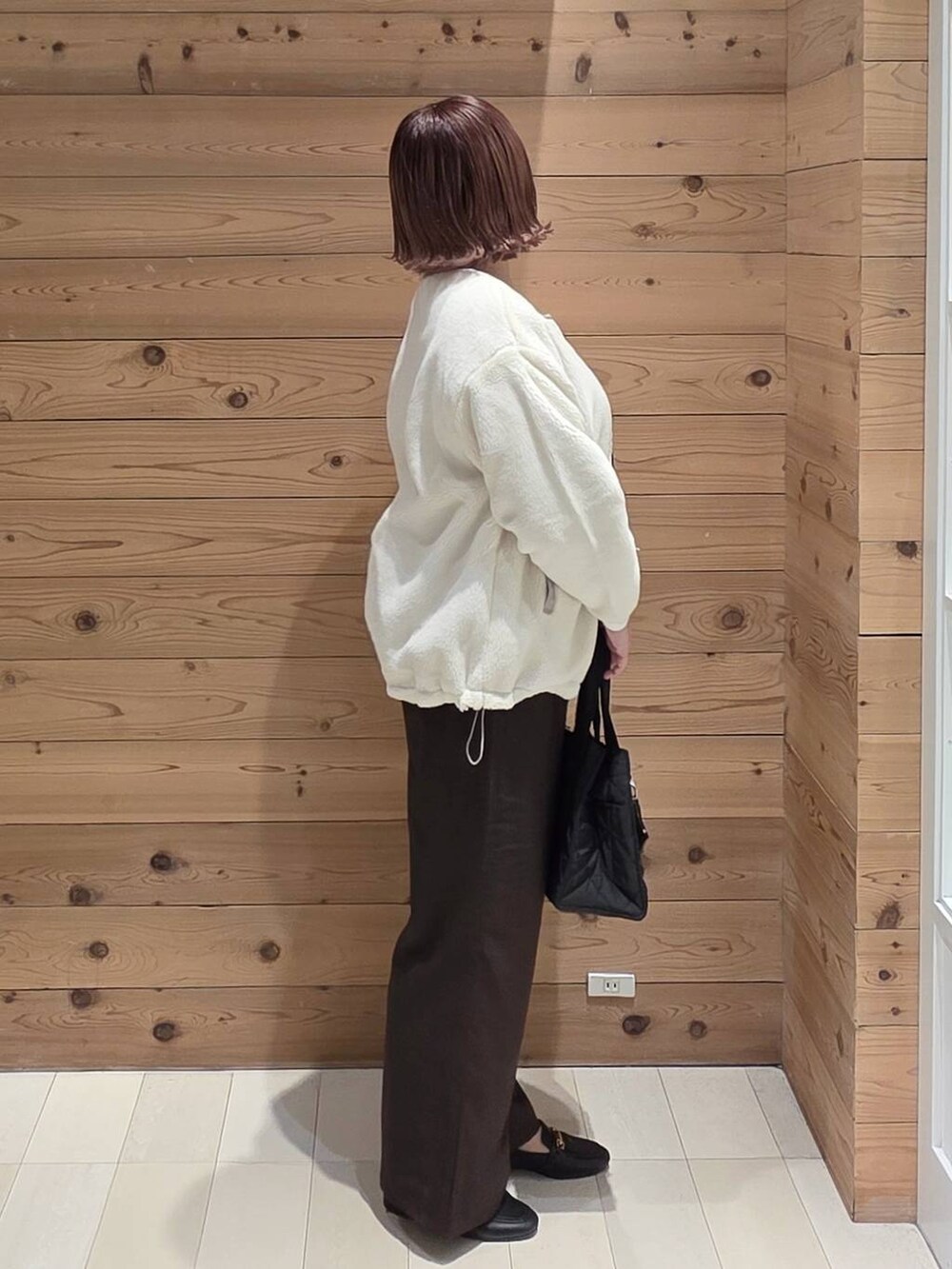 ブラック系のローファー、ブラック系のトートバッグ、ホワイト系のブルゾンを着用したレディースの秋コーディネートの2枚目の写真