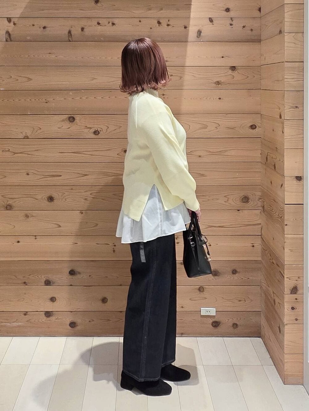 ブラック系のショルダーバッグ、ブルー系のデニムパンツ、ブラウン系のチェスターコートを着用したレディースの冬コーディネートの2枚目の写真