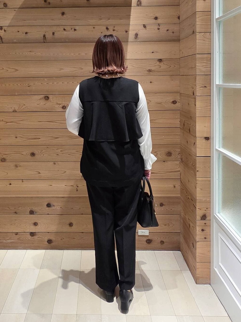 ブラック系のローファー、ブラック系のショルダーバッグ、ブラック系のセットアップを着用したレディースの冬コーディネートの3枚目の写真