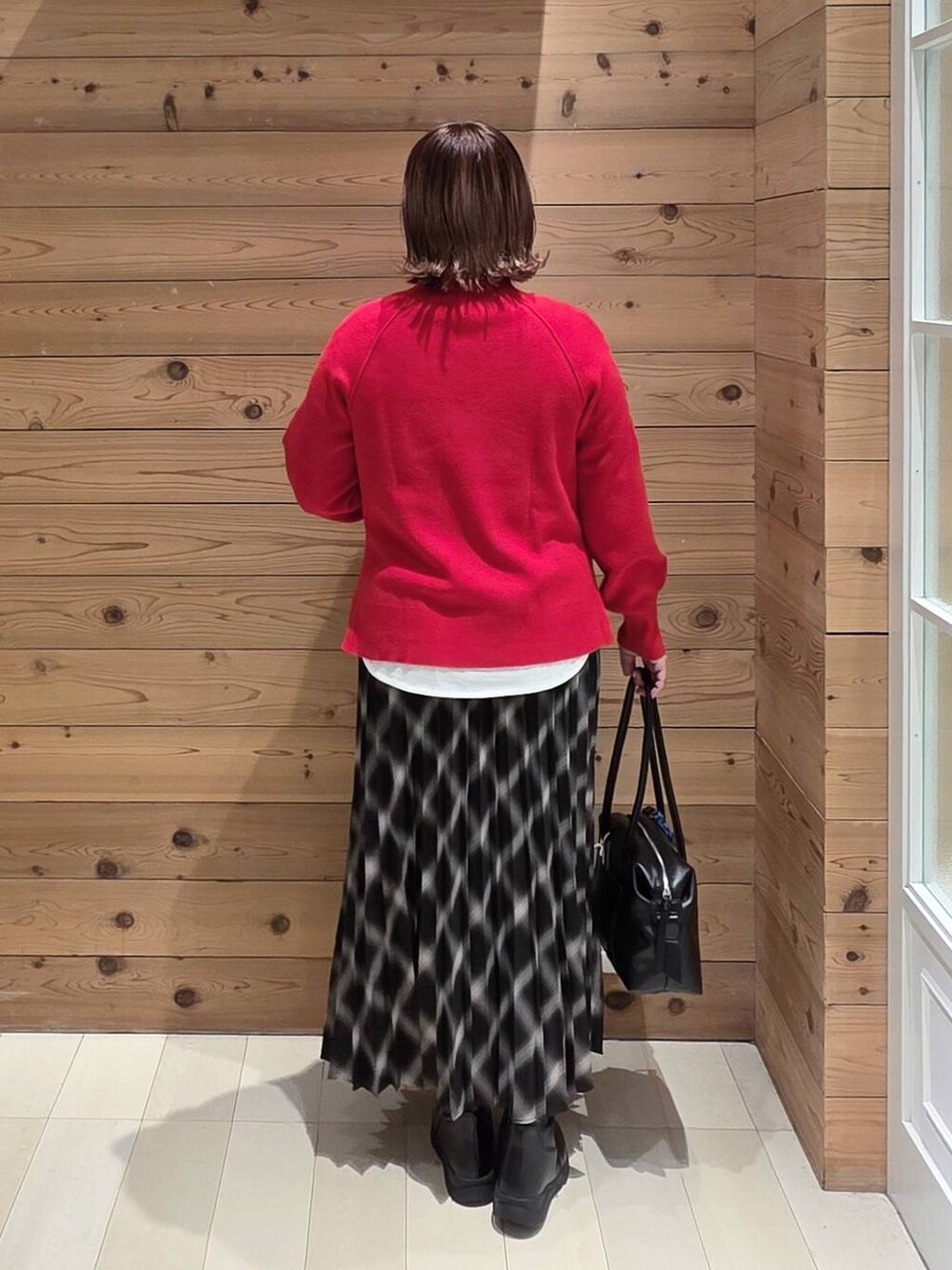 ブラック系のボストンバッグ、ベージュ系のブルゾン、ブラック系のブーツを着用したレディースの冬コーディネートの3枚目の写真