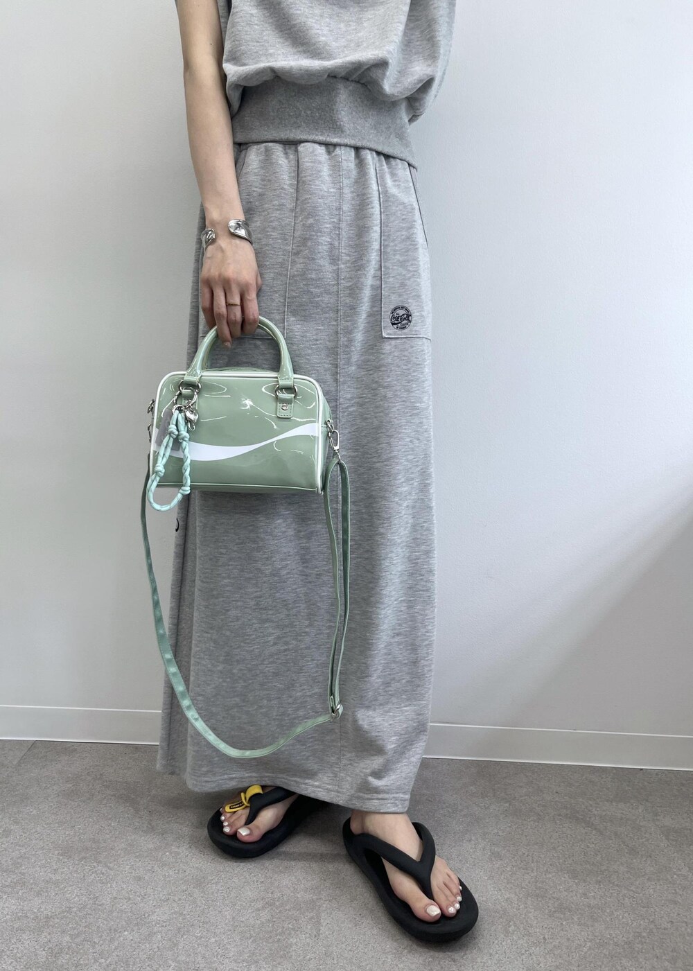 グレー系のスカート、グレー系のTシャツ/カットソー、グリーン系のボストンバッグを着用したレディースの夏コーディネートの8枚目の写真