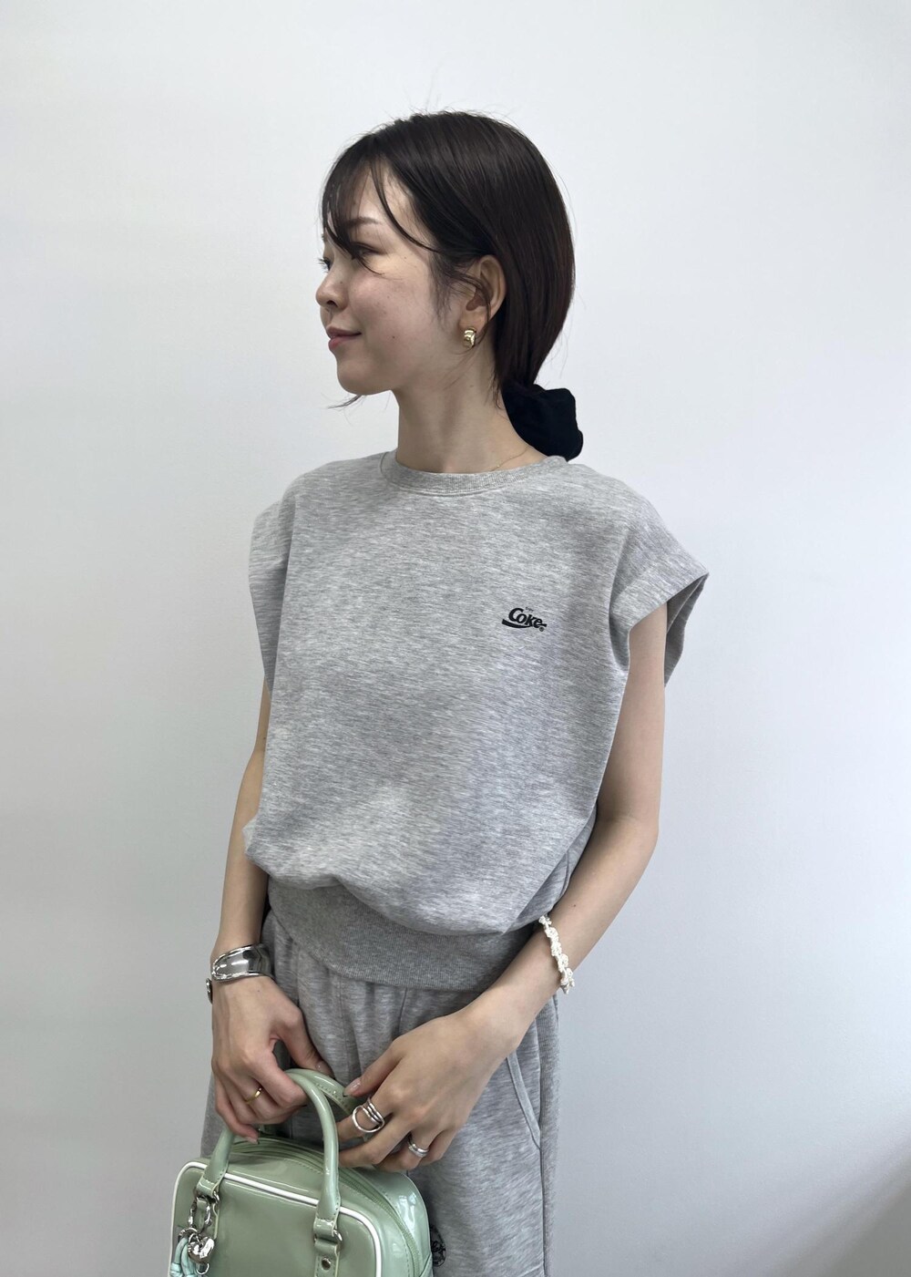 グレー系のスカート、グレー系のTシャツ/カットソー、グリーン系のボストンバッグを着用したレディースの夏コーディネートの6枚目の写真