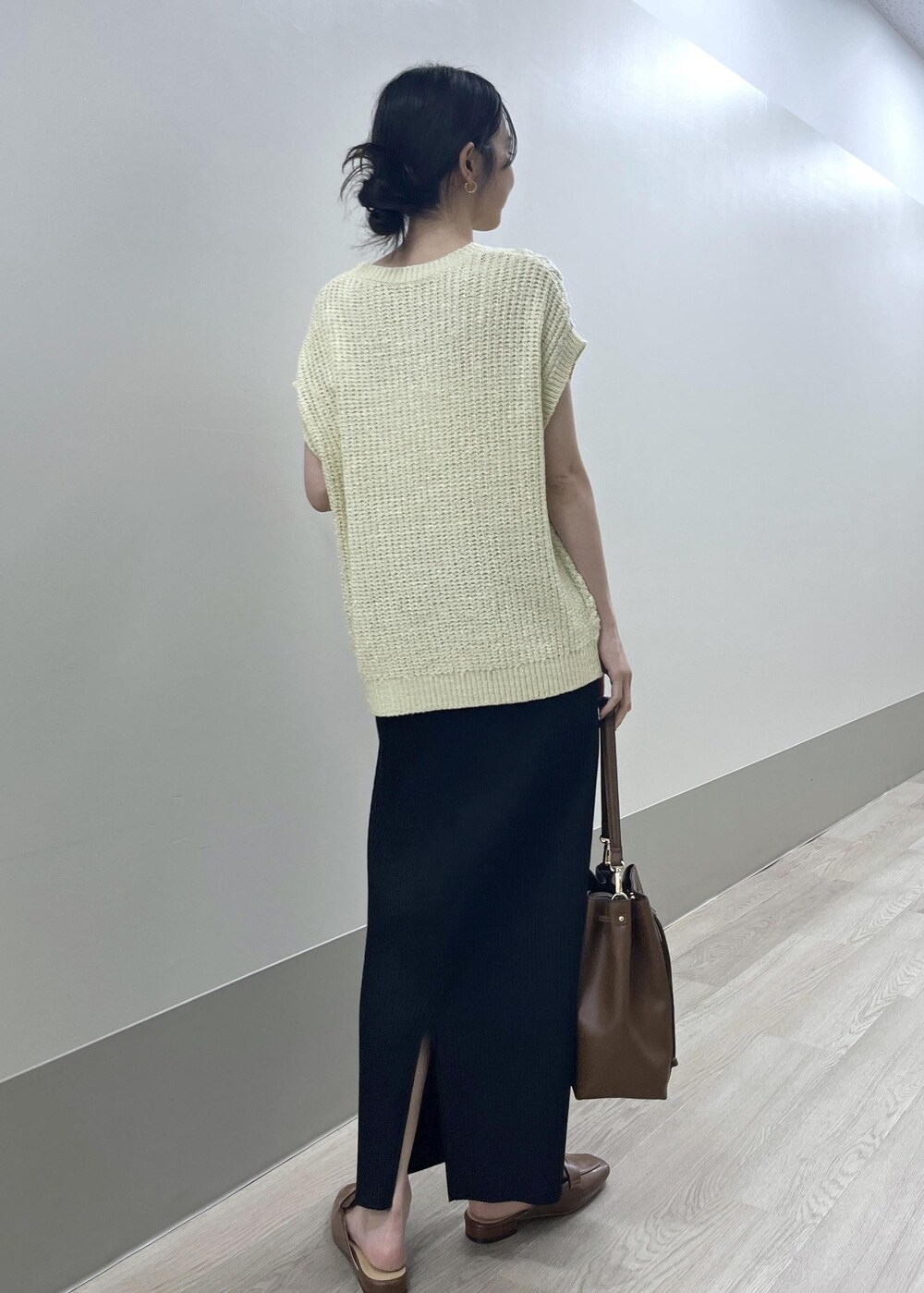 ブラック系のスカート、ベージュ系のベスト、ブラウン系のショルダーバッグを着用したレディースの夏コーディネートの5枚目の写真