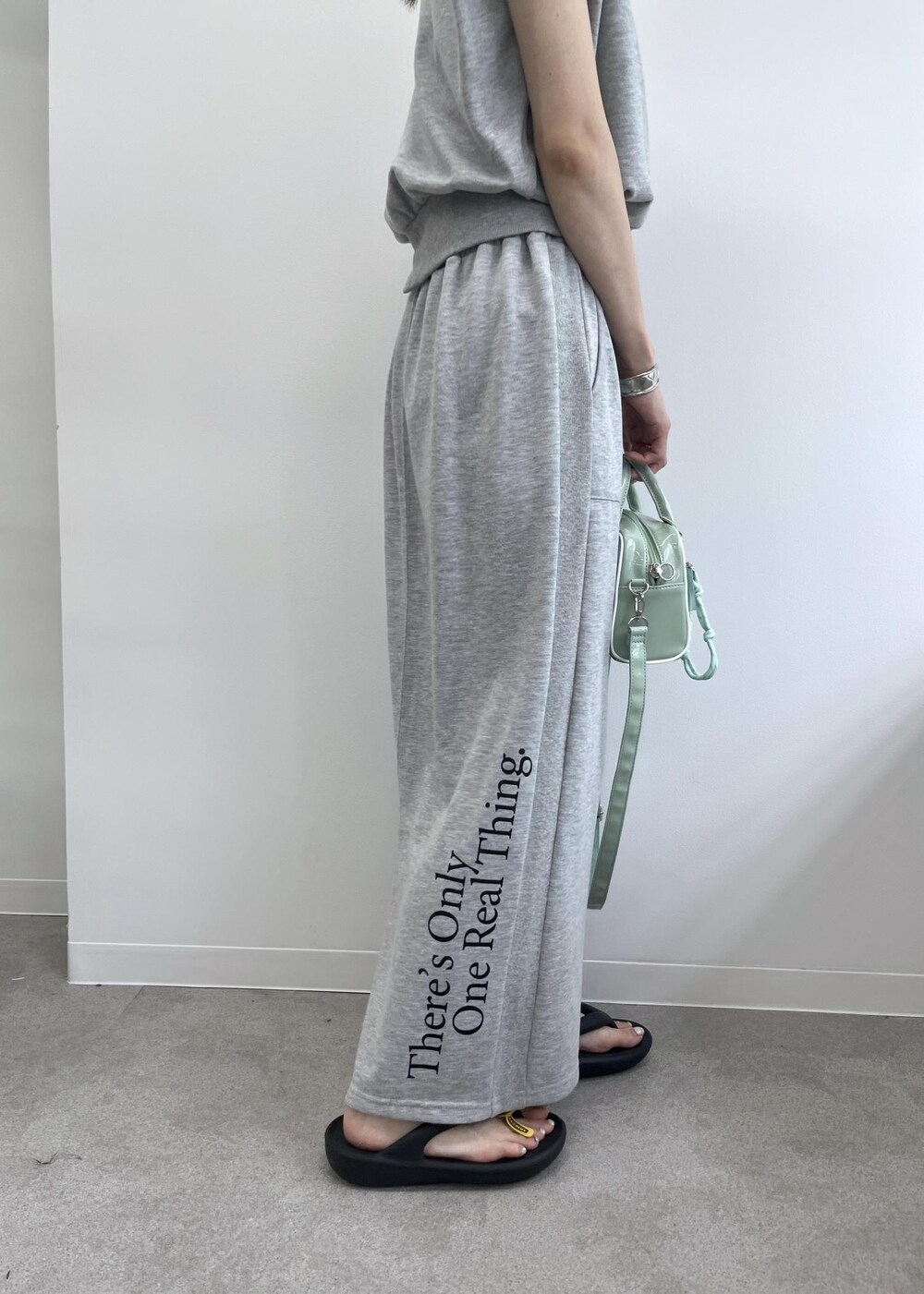 グレー系のスカート、グレー系のTシャツ/カットソー、グリーン系のボストンバッグを着用したレディースの夏コーディネートの7枚目の写真