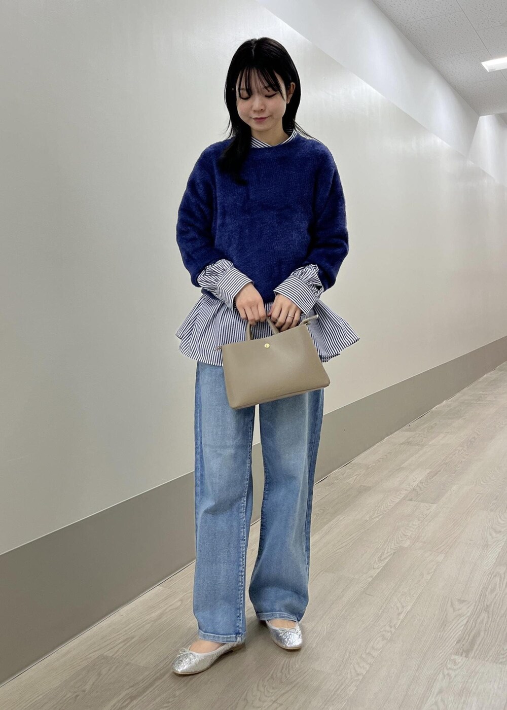 シルバー系のバレエシューズ、ブルー系のデニムパンツ、ベージュ系のショルダーバッグを着用したレディースの冬コーディネートの7枚目の写真