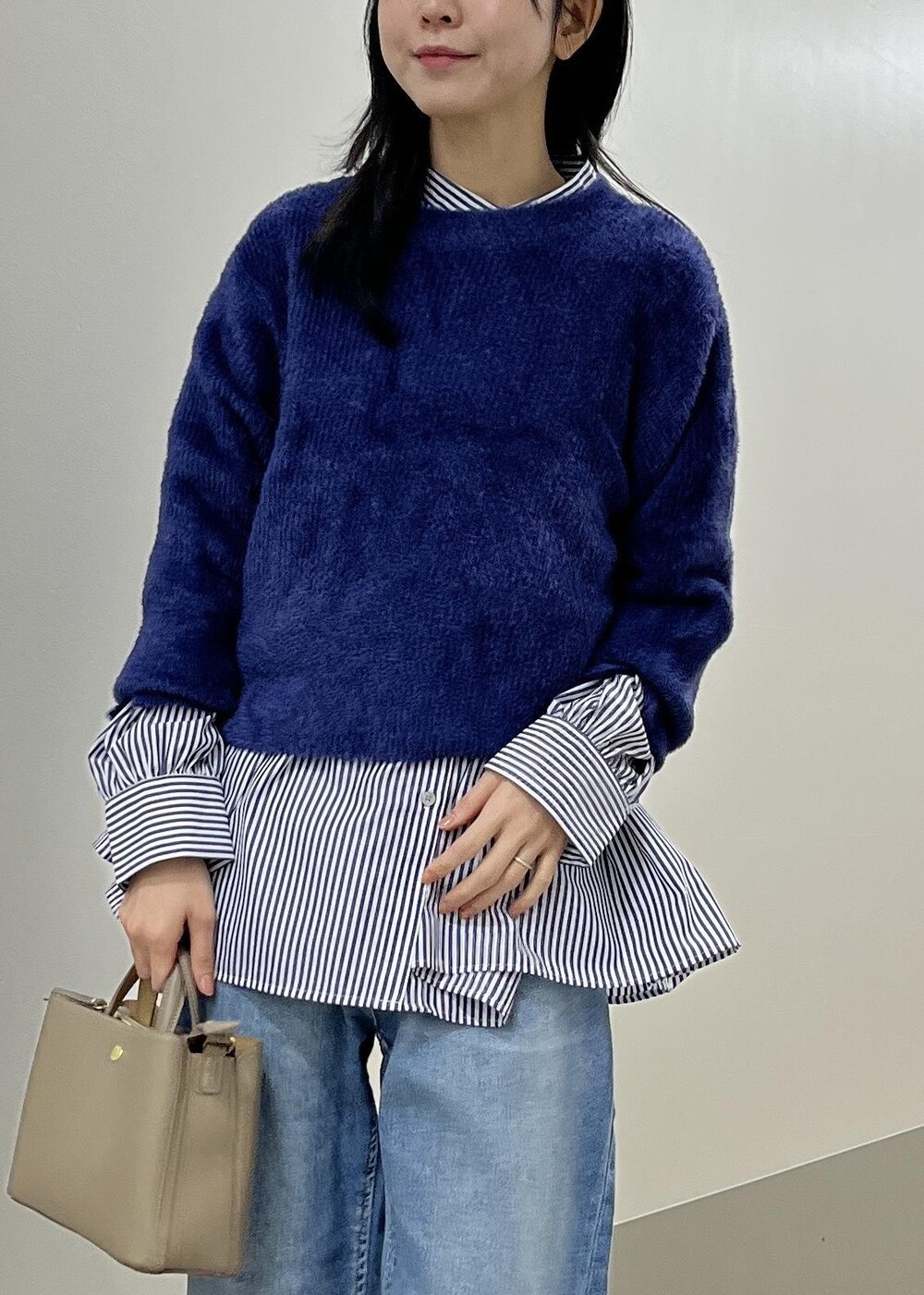 シルバー系のバレエシューズ、ブルー系のデニムパンツ、ベージュ系のショルダーバッグを着用したレディースの冬コーディネートの8枚目の写真