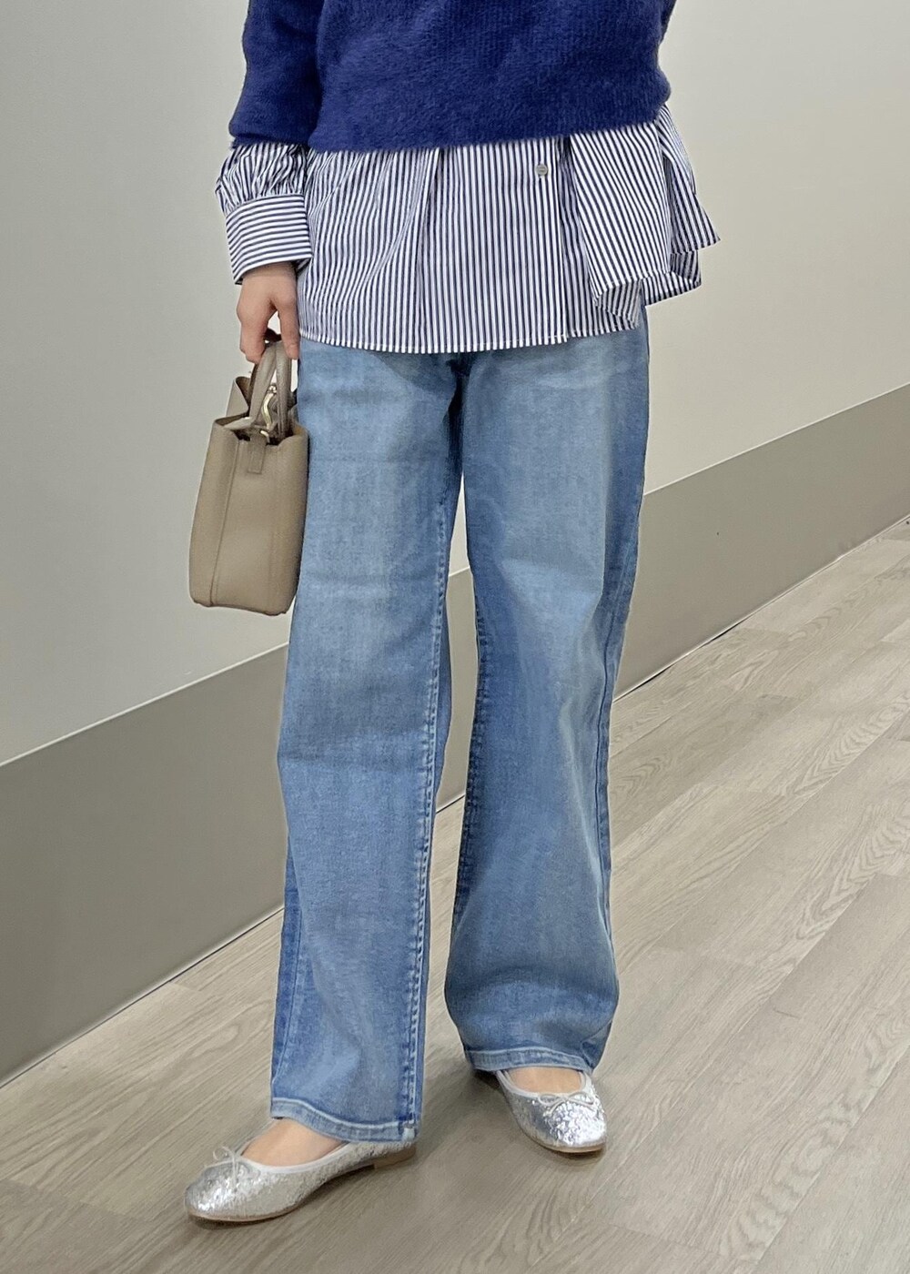 シルバー系のバレエシューズ、ブルー系のデニムパンツ、ベージュ系のショルダーバッグを着用したレディースの冬コーディネートの10枚目の写真