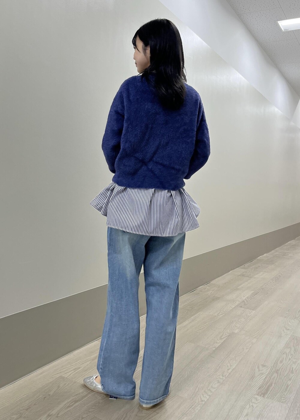 シルバー系のバレエシューズ、ブルー系のデニムパンツ、ベージュ系のショルダーバッグを着用したレディースの冬コーディネートの5枚目の写真