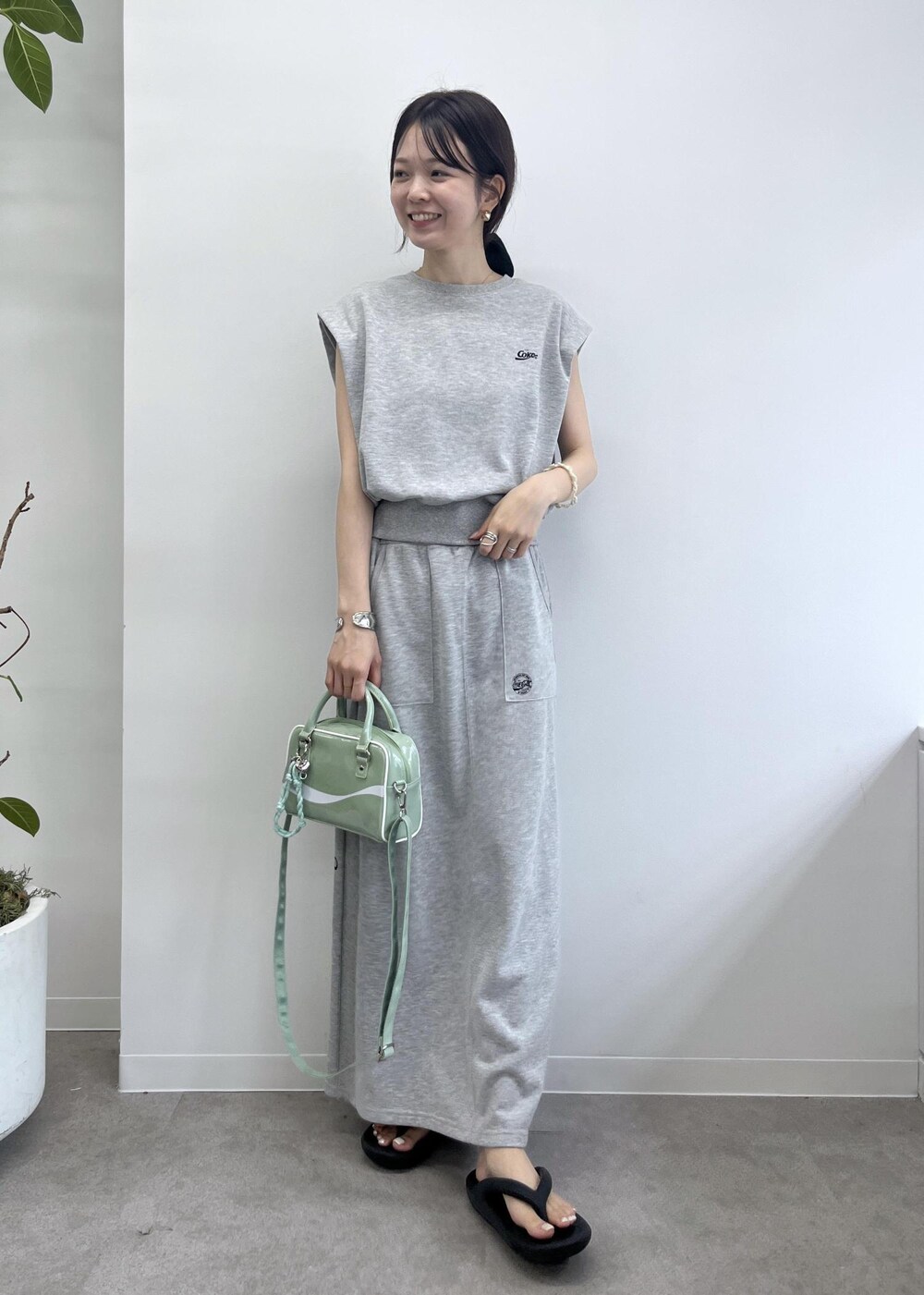 グレー系のスカート、グレー系のTシャツ/カットソー、グリーン系のボストンバッグを着用したレディースの夏コーディネートの2枚目の写真