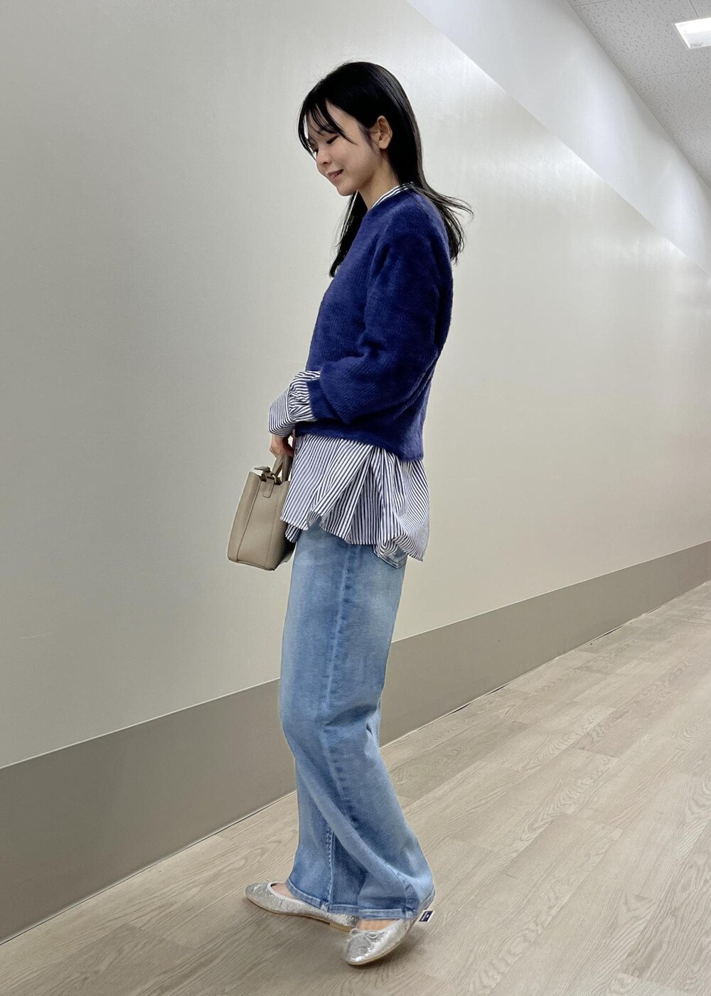 シルバー系のバレエシューズ、ブルー系のデニムパンツ、ベージュ系のショルダーバッグを着用したレディースの冬コーディネートの3枚目の写真