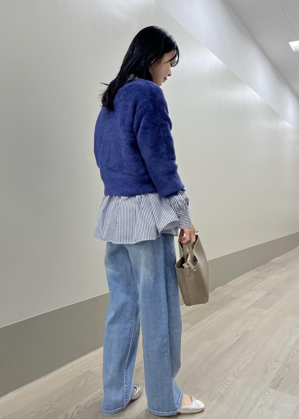 シルバー系のバレエシューズ、ブルー系のデニムパンツ、ベージュ系のショルダーバッグを着用したレディースの冬コーディネートの6枚目の写真