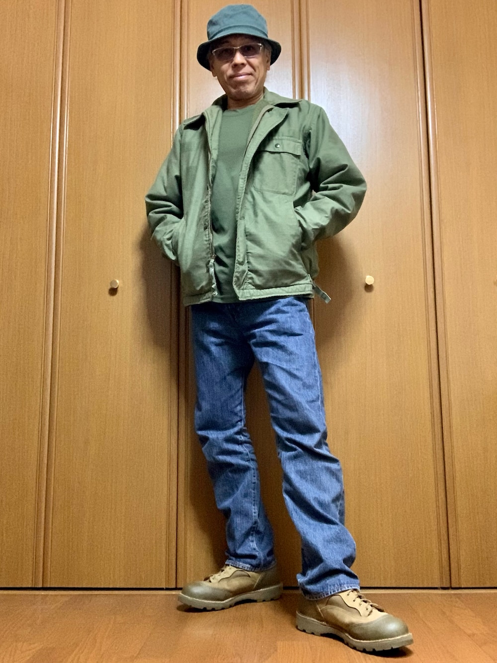 グリーン系のTシャツ/カットソー、グリーン系のミリタリージャケット、ブルー系のデニムパンツを着用したメンズの冬コーディネートの3枚目の写真