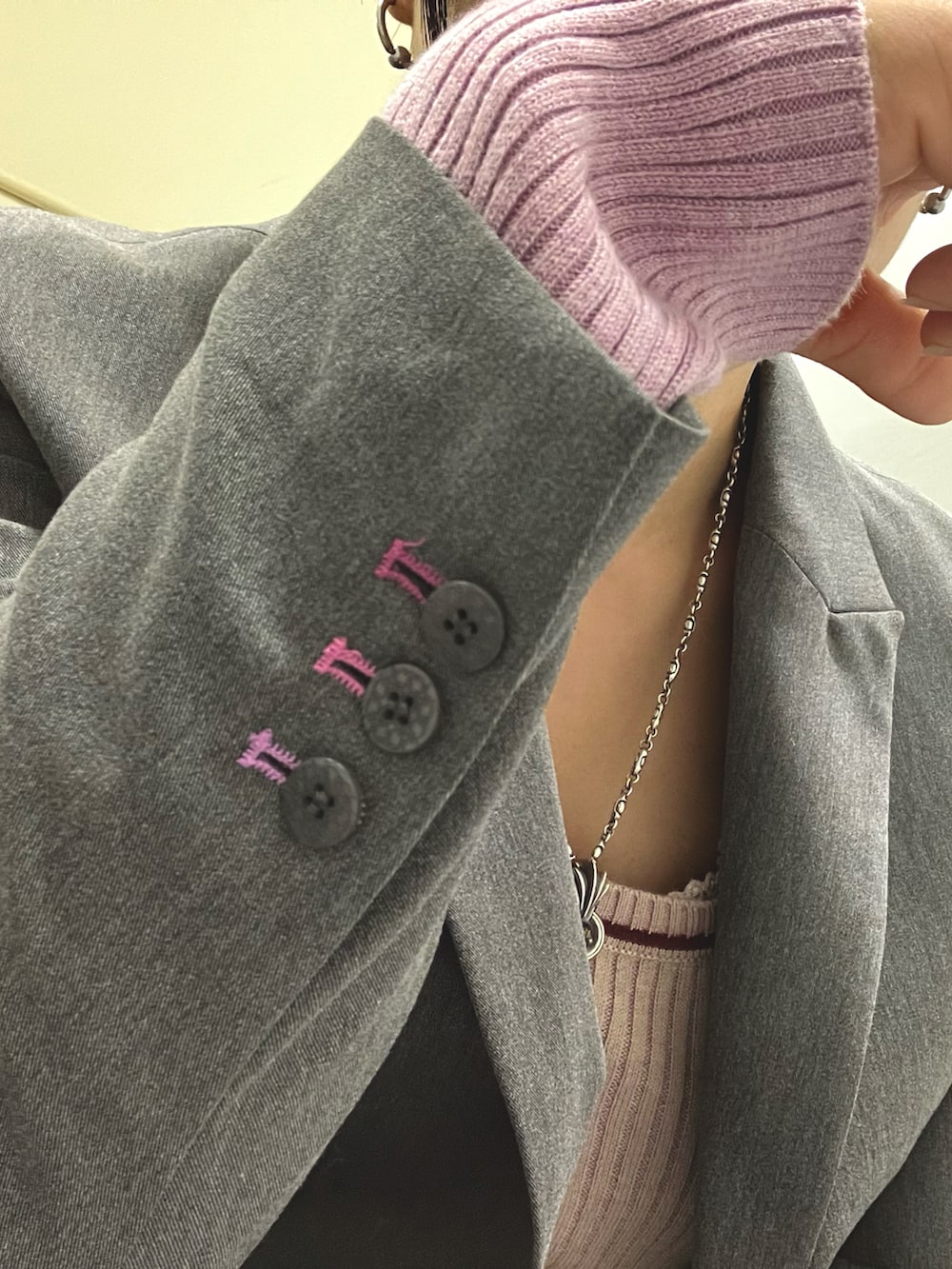 ピンク系のニット/セーター、グレー系のテーラードジャケット、グレー系のスラックスを着用したレディースの秋コーディネートの4枚目の写真