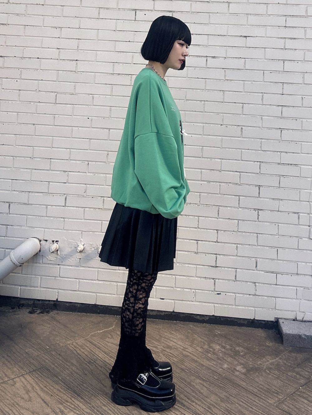 グリーン系のスウェット、ブラック系のスカート、ブラック系のその他パンツを着用したレディースの冬コーディネートの3枚目の写真