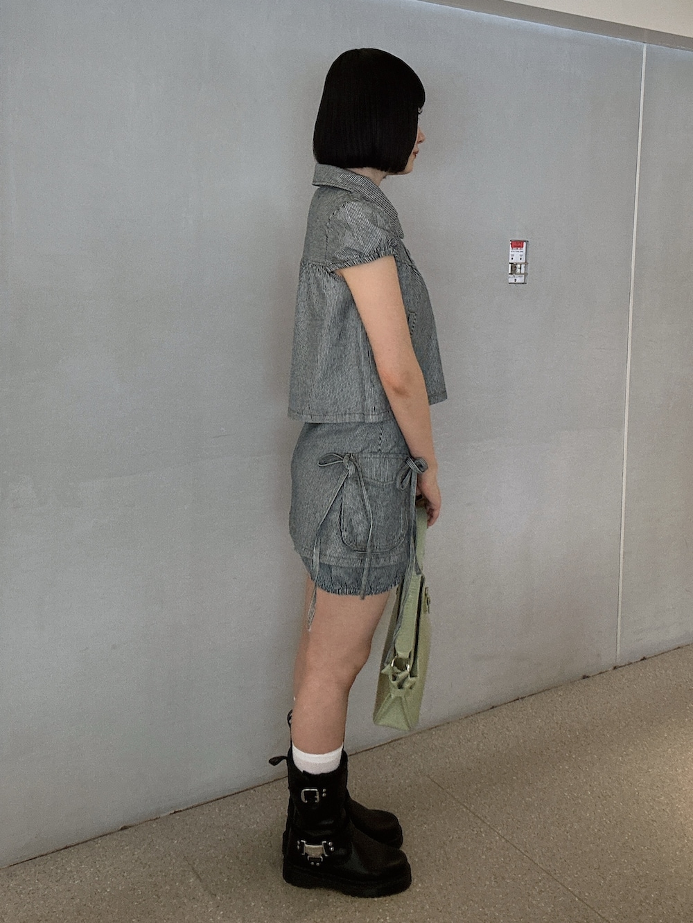 ブラック系のその他トップス、ブラック系のデニムパンツ、グリーン系のハンドバッグを着用したレディースの春コーディネートの2枚目の写真