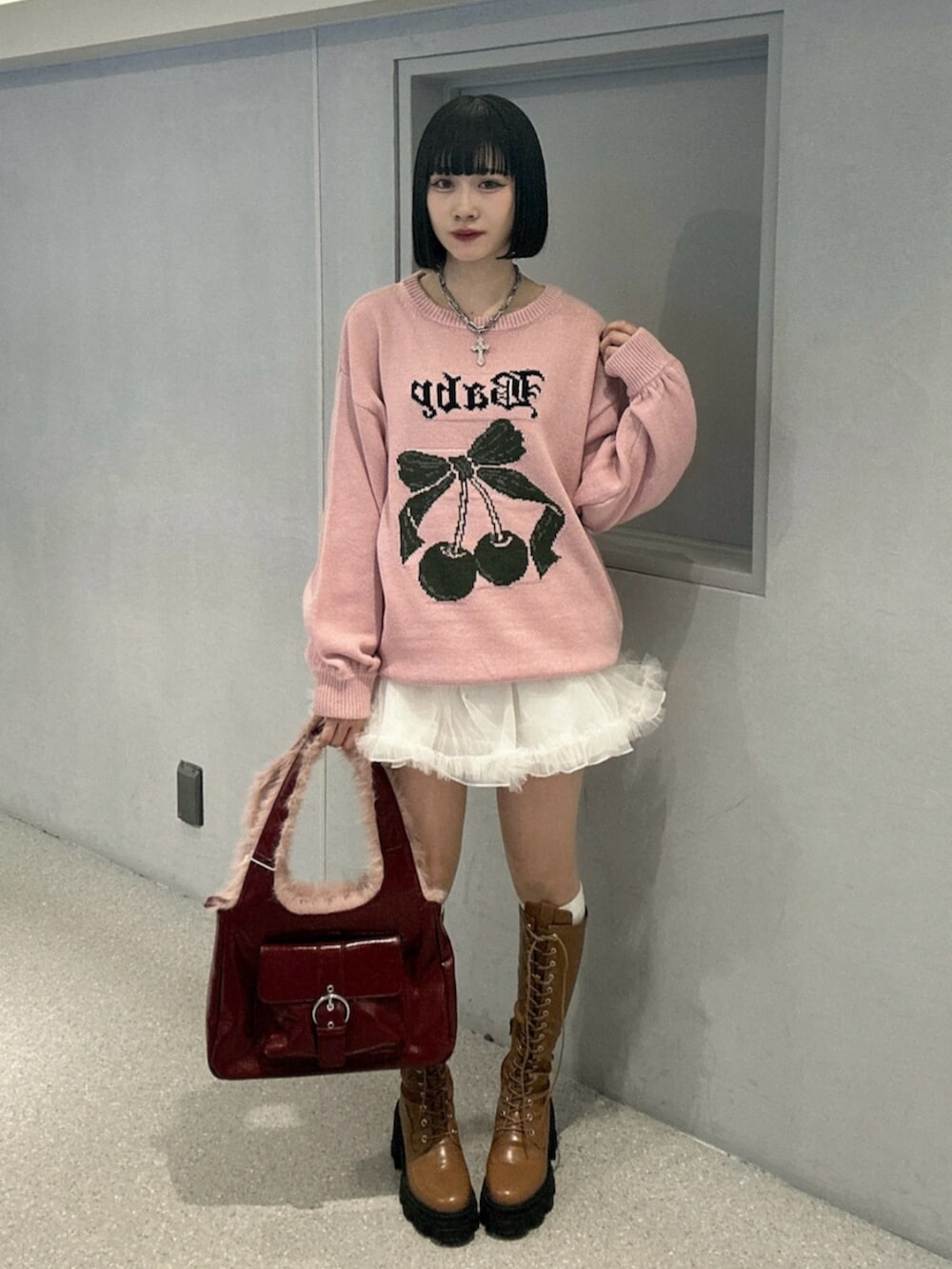 ホワイト系のニット/セーター、ホワイト系のスカート、ブラウン系のブーツを着用したレディースの秋コーディネートの4枚目の写真