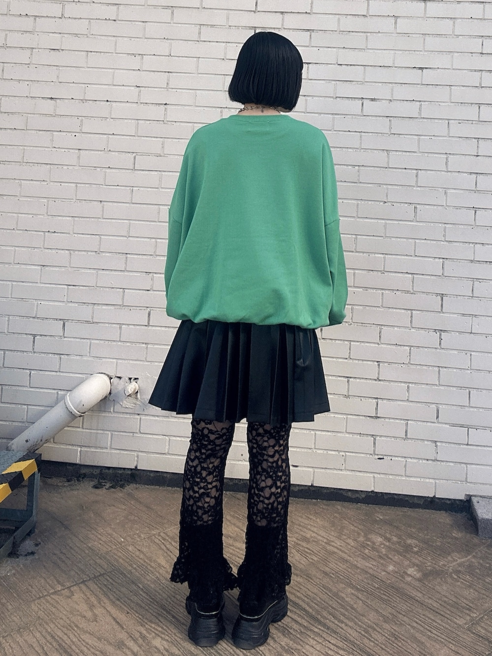 グリーン系のスウェット、ブラック系のスカート、ブラック系のその他パンツを着用したレディースの冬コーディネートの2枚目の写真