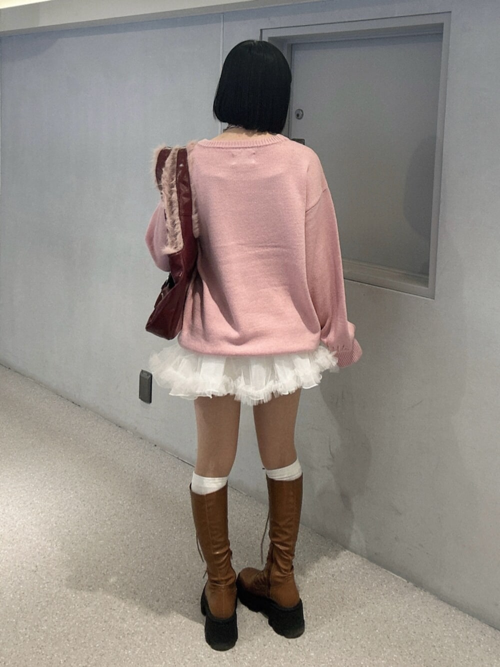 ホワイト系のニット/セーター、ホワイト系のスカート、ブラウン系のブーツを着用したレディースの秋コーディネートの3枚目の写真