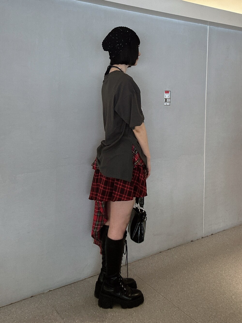 ブラック系のTシャツ/カットソー、レッド系のスカート、ブラック系のブーツを着用したレディースの春コーディネートの2枚目の写真