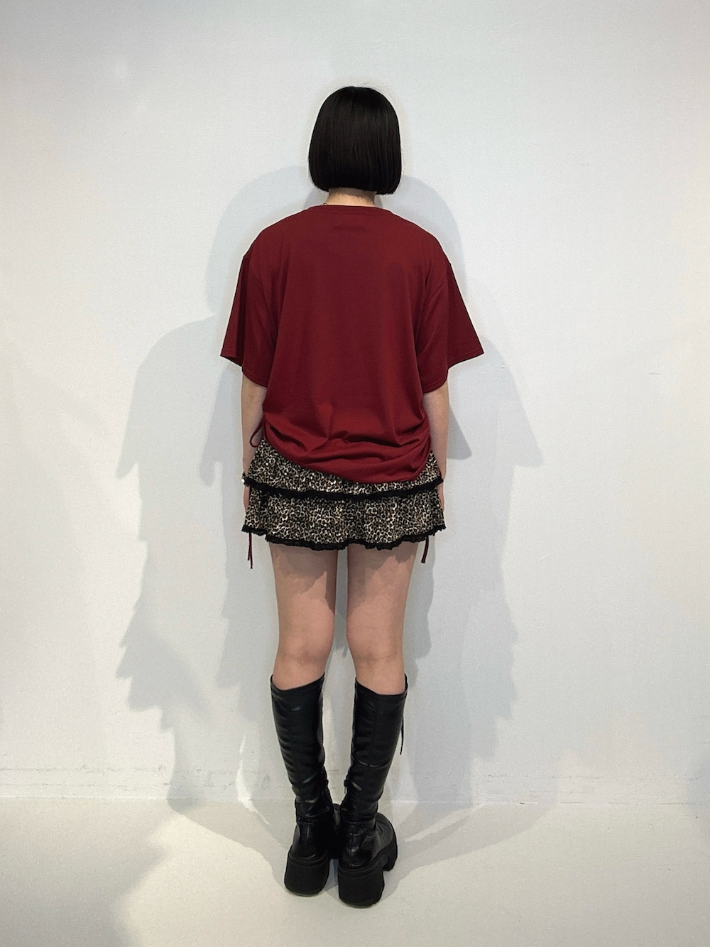 レッド系のTシャツ/カットソー、ブラウン系のスカート、ブラック系のブーツを着用したレディースの夏コーディネートの3枚目の写真