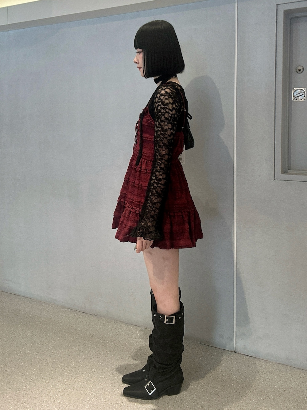 レッド系のワンピース、ブラック系のTシャツ/カットソー、ブラック系のブーツを着用したレディースの冬コーディネートの2枚目の写真