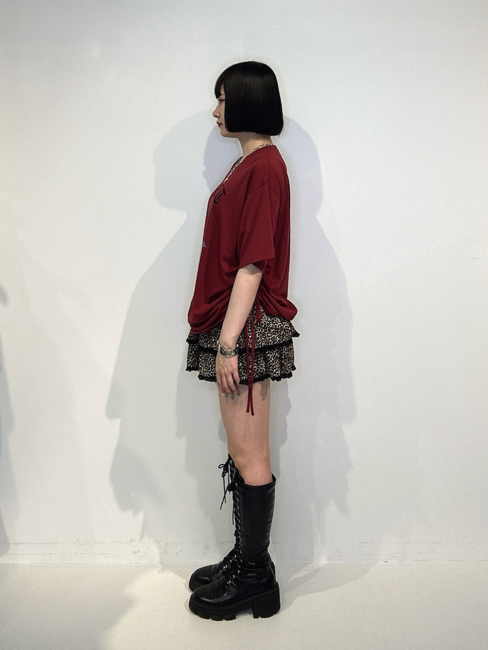 レッド系のTシャツ/カットソー、ブラウン系のスカート、ブラック系のブーツを着用したレディースの夏コーディネートの2枚目の写真
