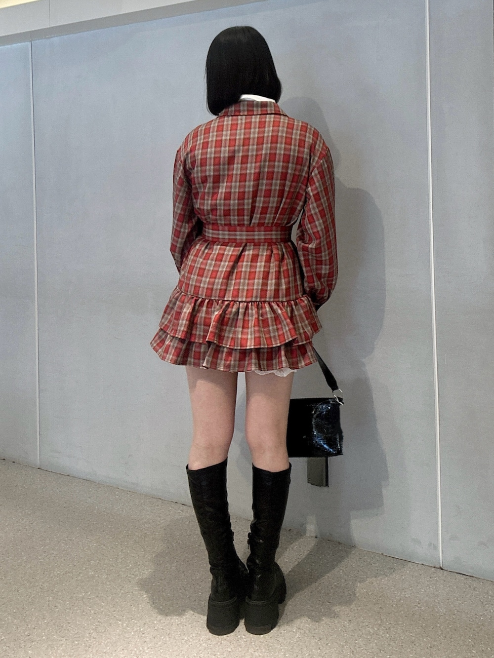 レッド系のワンピース、ブラック系のブーツ、ブラック系のハンドバッグを着用したレディースの冬コーディネートの3枚目の写真