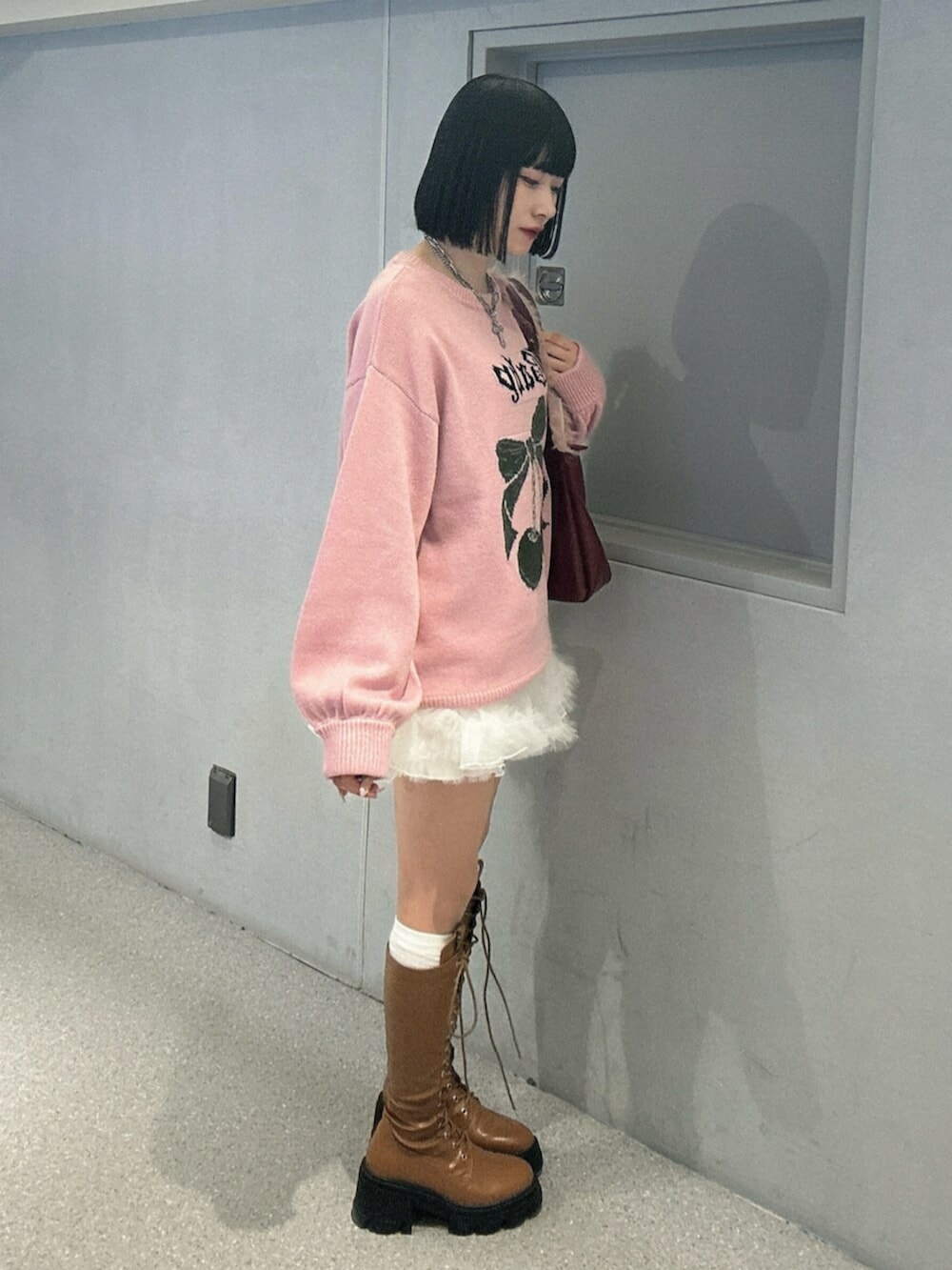 ホワイト系のニット/セーター、ホワイト系のスカート、ブラウン系のブーツを着用したレディースの秋コーディネートの2枚目の写真