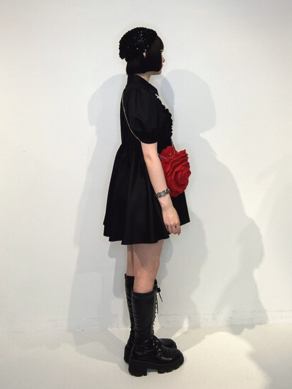 ブラック系のブーツ、ブラック系のワンピース、レッド系のショルダーバッグを着用したレディースの夏コーディネートの2枚目の写真