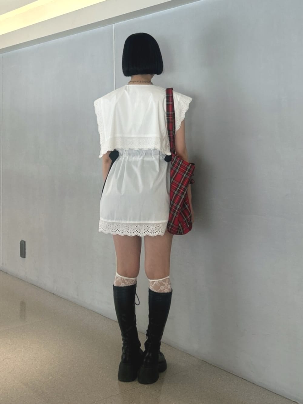 ブラック系のブーツ、ホワイト系のシャツ/ブラウス、レッド系のトートバッグを着用したレディースの夏コーディネートの3枚目の写真