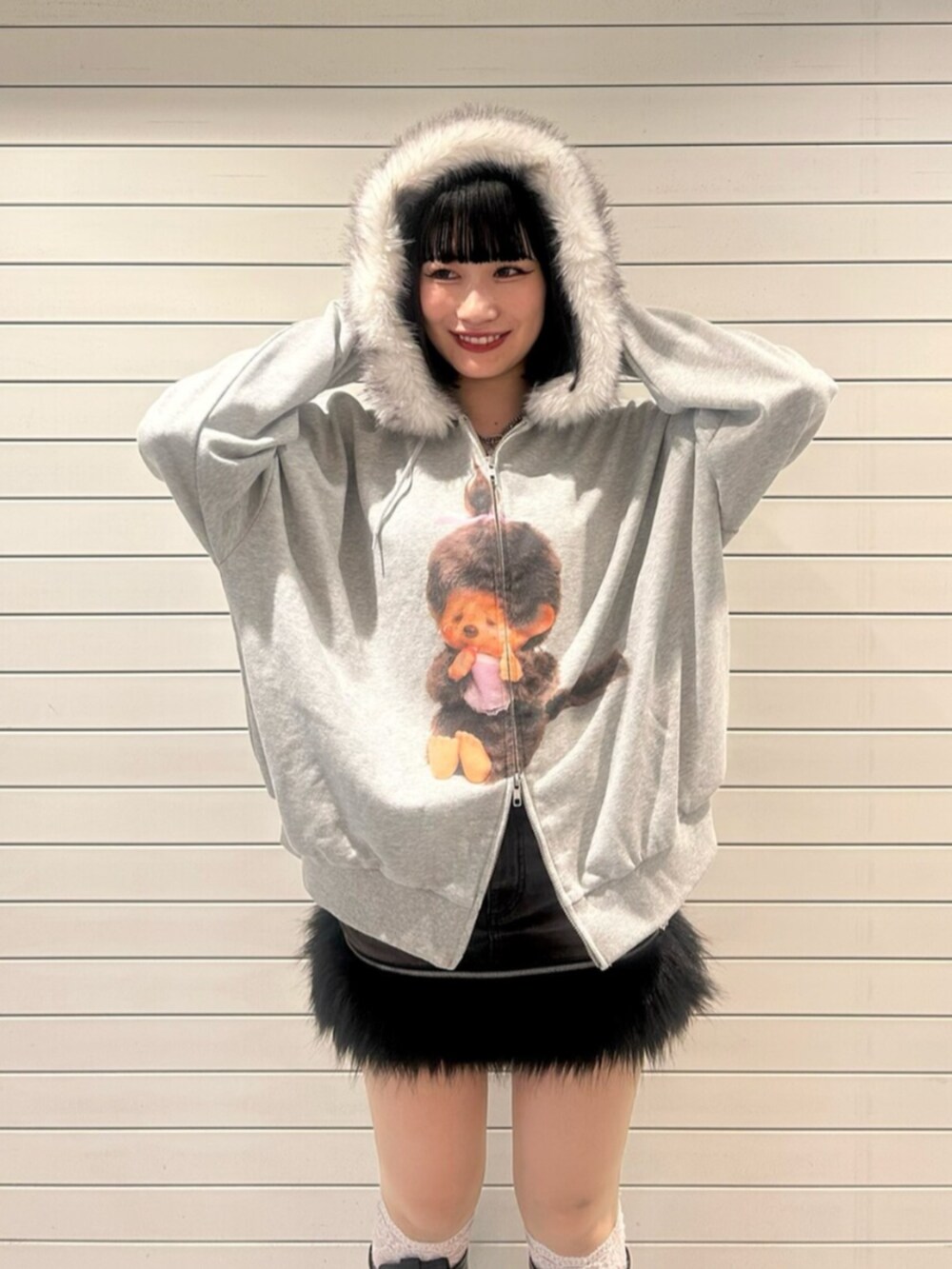 グレー系のパーカー、ブラック系のスカート、ブラック系のブーツを着用したレディースの秋コーディネートの5枚目の写真