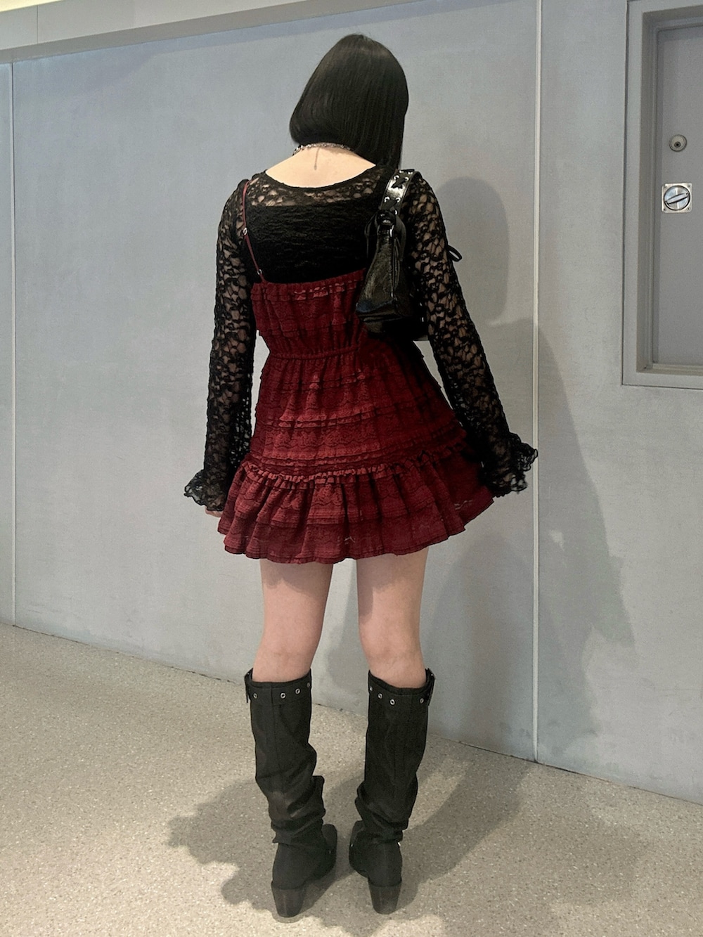 レッド系のワンピース、ブラック系のTシャツ/カットソー、ブラック系のブーツを着用したレディースの冬コーディネートの3枚目の写真