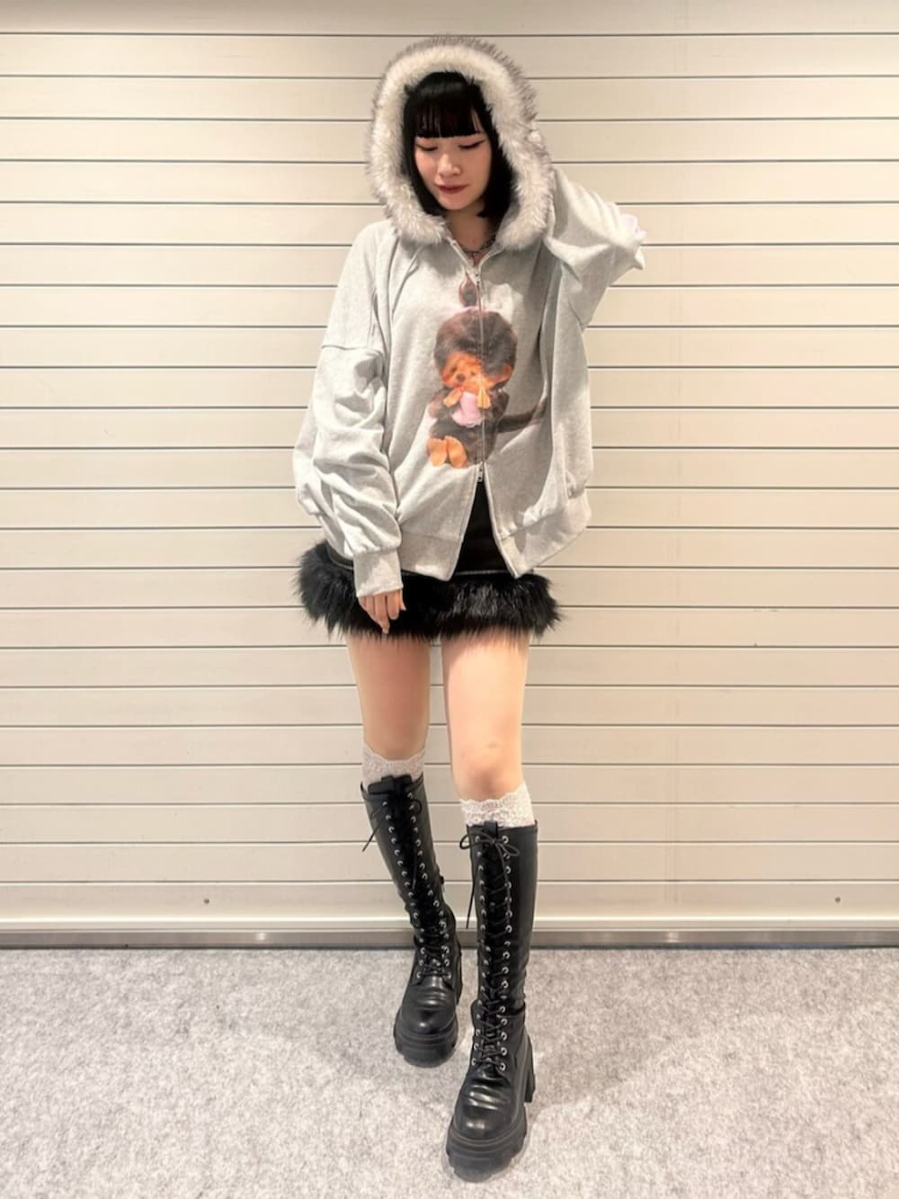 グレー系のパーカー、ブラック系のスカート、ブラック系のブーツを着用したレディースの秋コーディネートの4枚目の写真