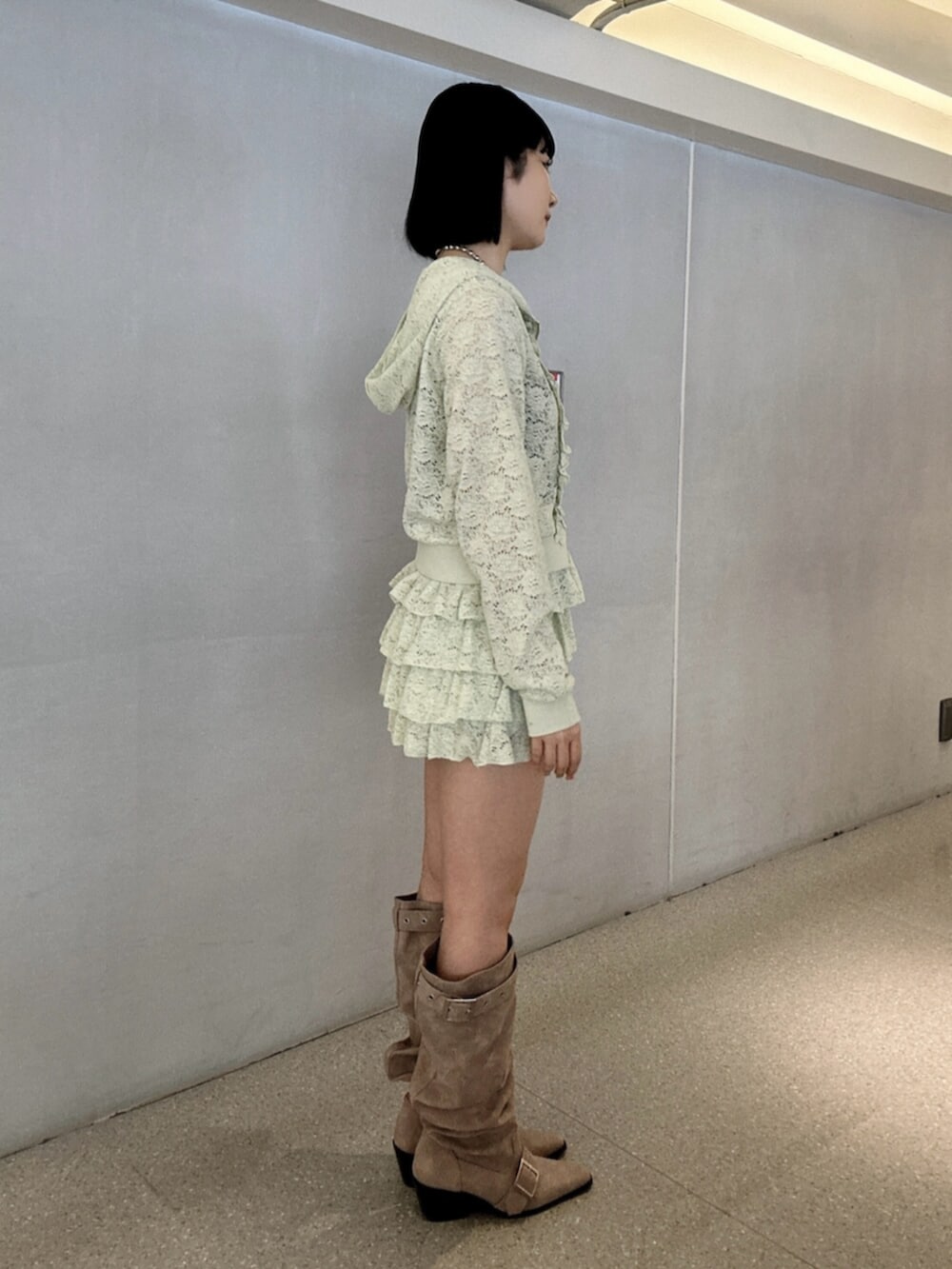 グリーン系のパーカー、グリーン系のスカート、ピンク系のブーツを着用したレディースの春コーディネートの2枚目の写真