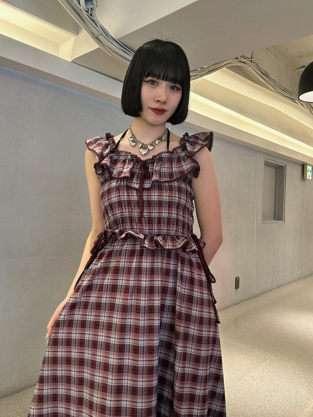 レッド系のワンピース、ブラック系のブーツ、シルバー系のネックレスを着用したレディースの春コーディネートの4枚目の写真