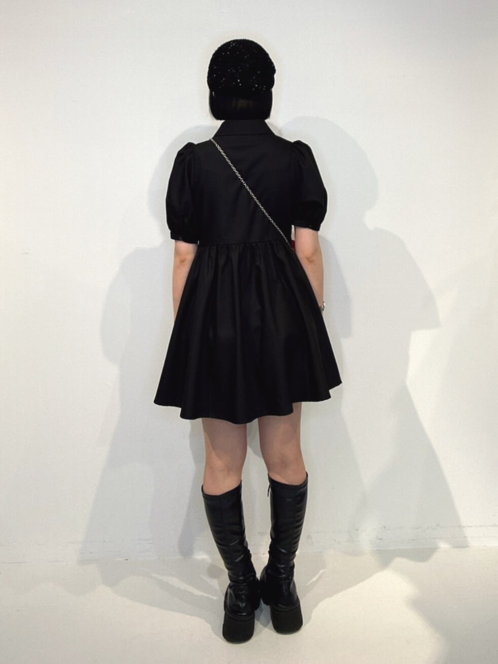ブラック系のブーツ、ブラック系のワンピース、レッド系のショルダーバッグを着用したレディースの夏コーディネートの3枚目の写真