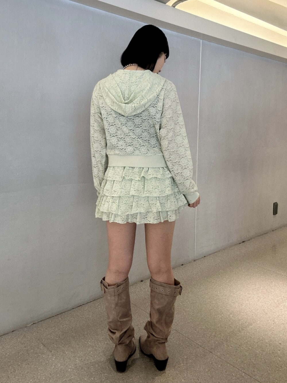 グリーン系のパーカー、グリーン系のスカート、ピンク系のブーツを着用したレディースの春コーディネートの3枚目の写真