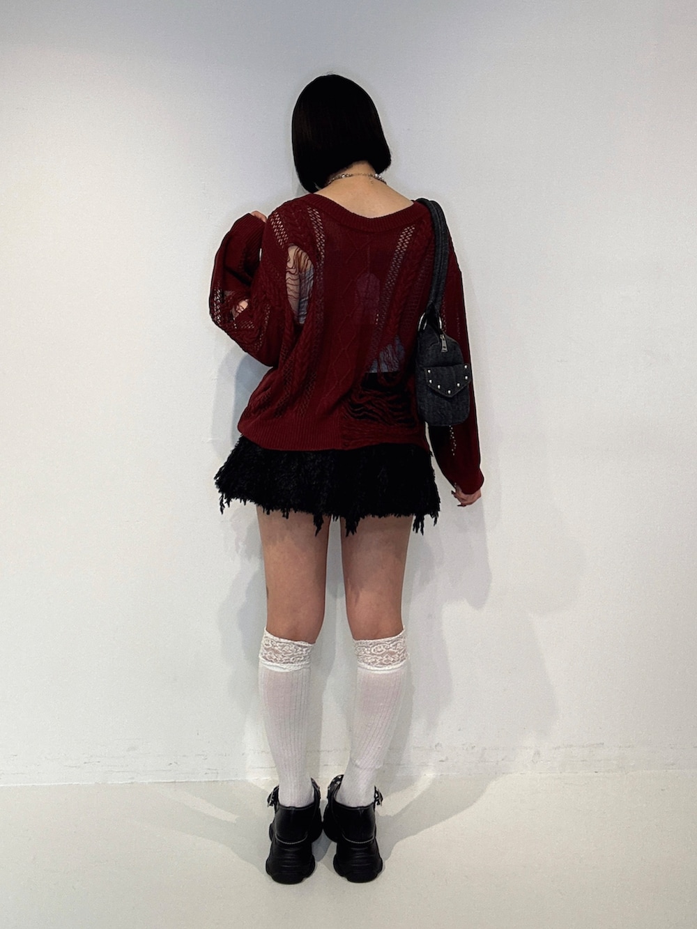レッド系のニット/セーター、ブラック系のスカート、ブラック系のサンダルを着用したレディースの夏コーディネートの3枚目の写真