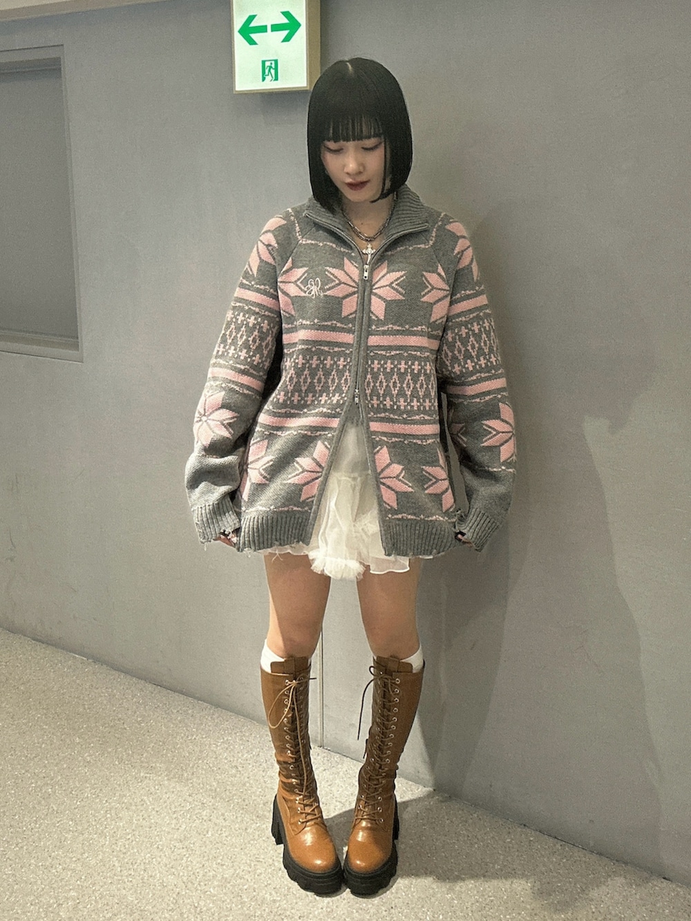 グレー系のカーディガン/ボレロ、ホワイト系のスカート、ブラウン系のブーツを着用したレディースの秋コーディネートの2枚目の写真