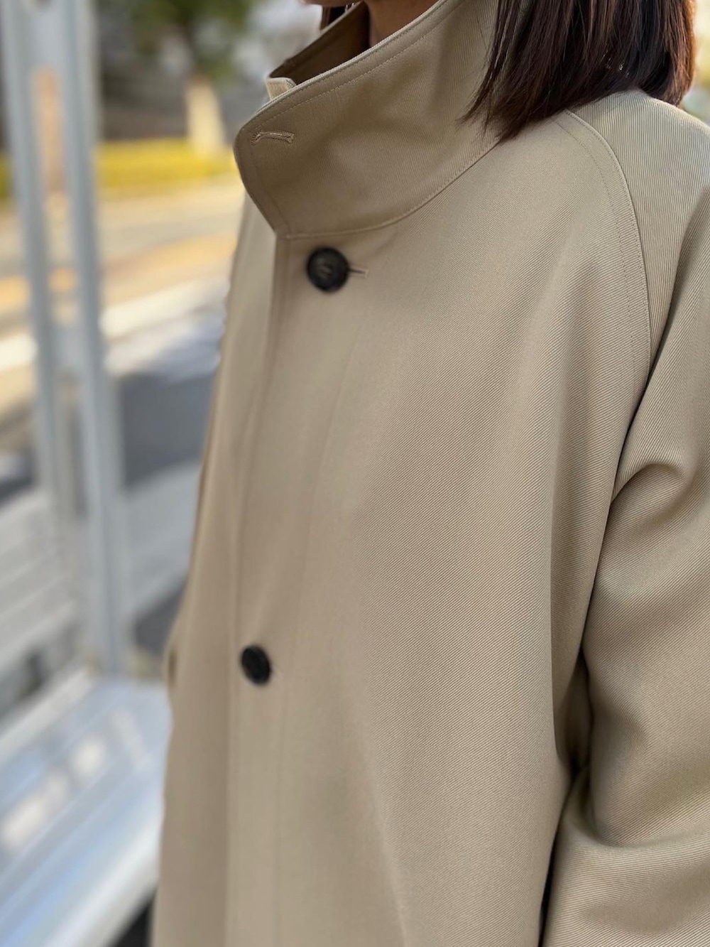 ベージュ系のステンカラーコートを着用したレディースの秋コーディネートの2枚目の写真