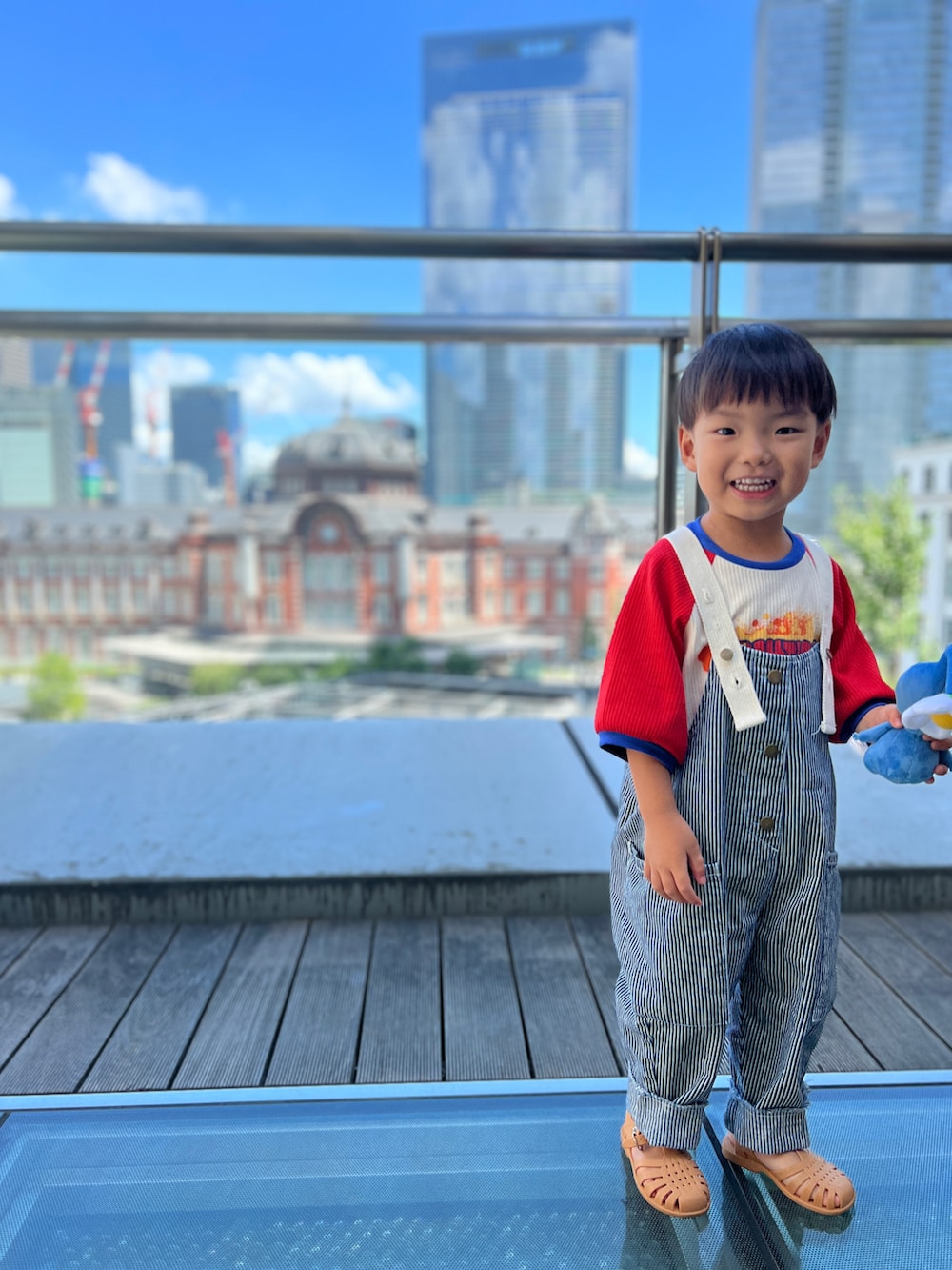 レッド系のTシャツ/カットソー、ブルー系のサロペット/オーバーオール、ベージュ系のサンダルを着用したキッズの夏コーディネートの2枚目の写真